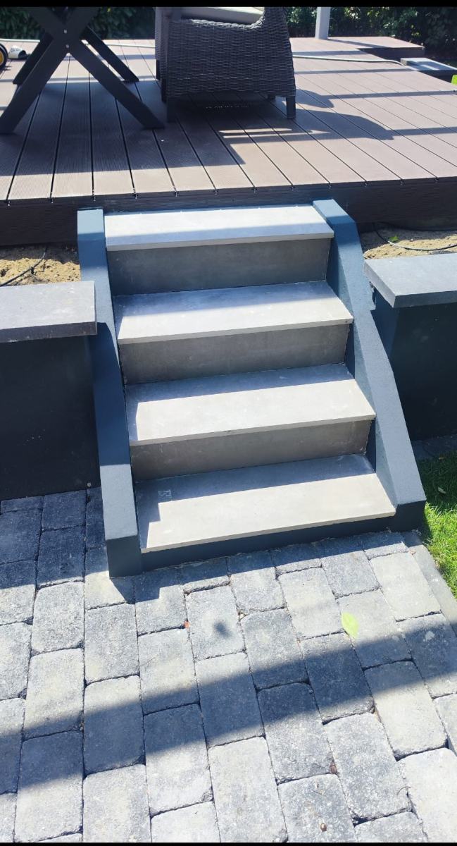 Fertige Treppe mit grauen Steinstufen von der Terrasse zum gepflasterten Weg